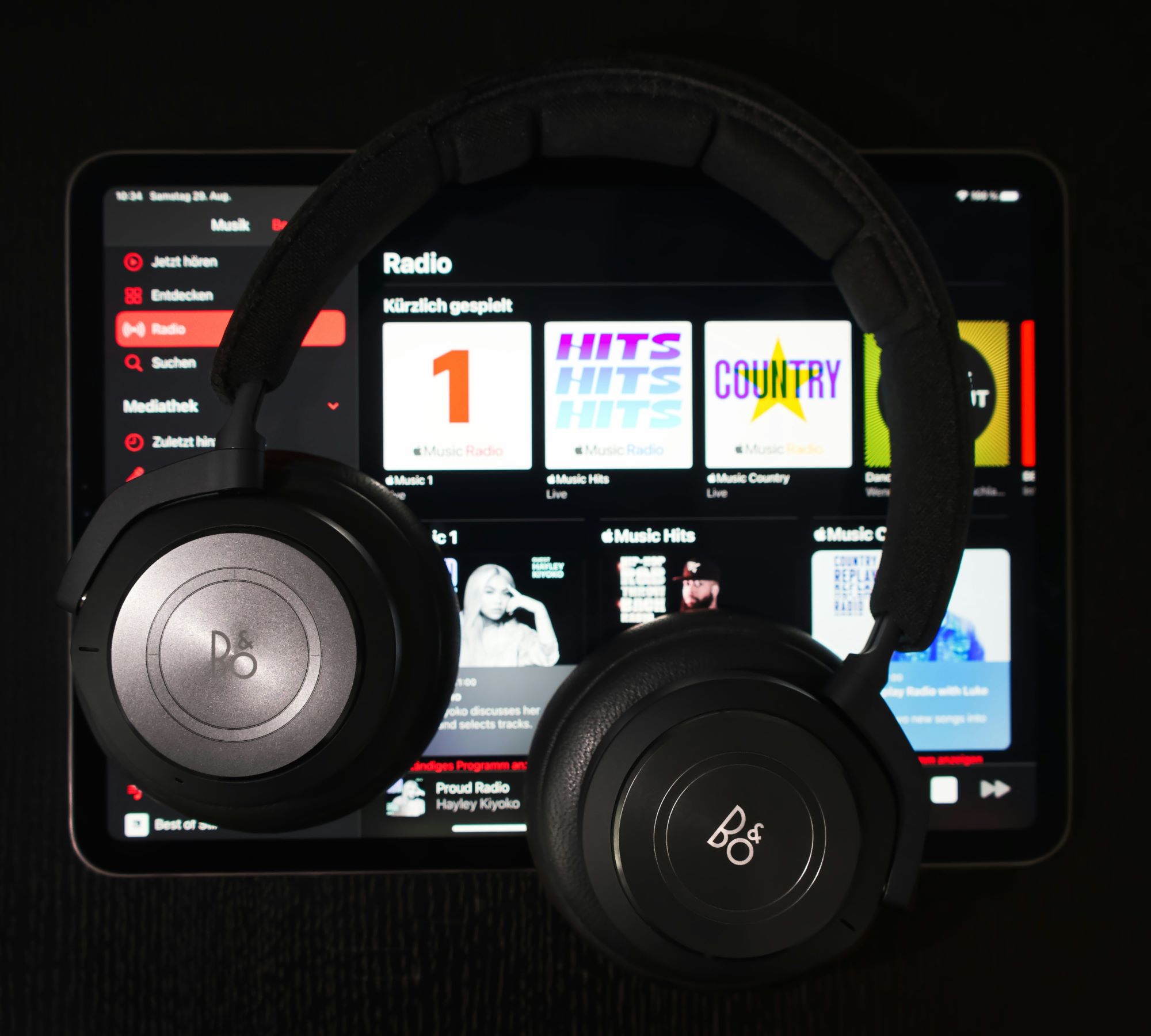 Hörlurar på en iPad som visar Apple Music streaming tjänst. Illustrerar AI genererad musik streaming.