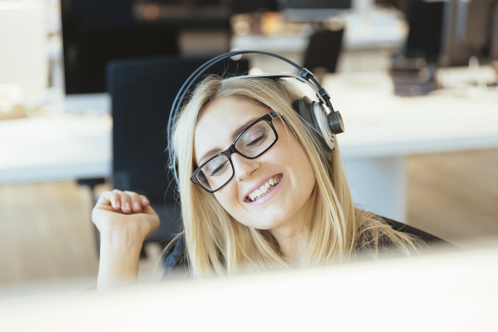 Kvinna med hörlurar framför dator under digitalt möte med klient om business consulting tjänster.