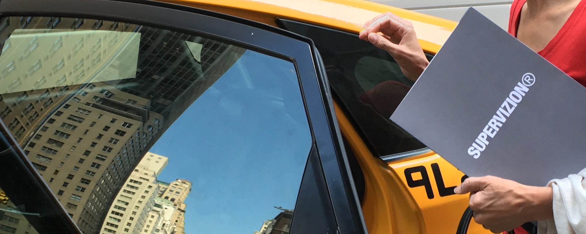 Fotomodell kliver in i taxi i New York och håller i folder från Supervizion.